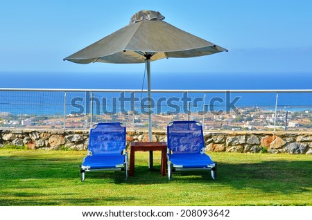 Lounge Chairs by the Pool - a pair of blue lounge chairs by the pool in Maila, Crete, Greece, with the blue see in the background