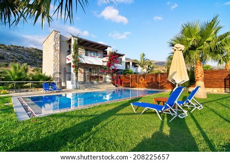 MALIA, GREECE - JULY 21, 2014: Villa with a private pool and garden on a summer vacation in golden hour light.  Malia, Crete near Hersonissos and Heraklion.