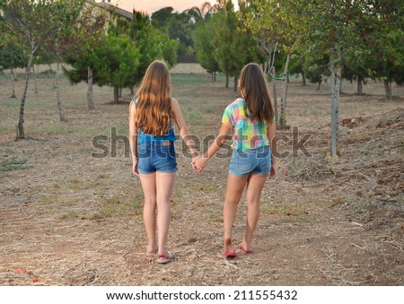 Best Friends Forever - two 12 year old teenage girls  holding hands at sunset