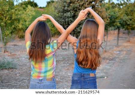Best Friends Forever - two 12 year old teenage girls  holding hands in an infinity forever sign to signify BFF