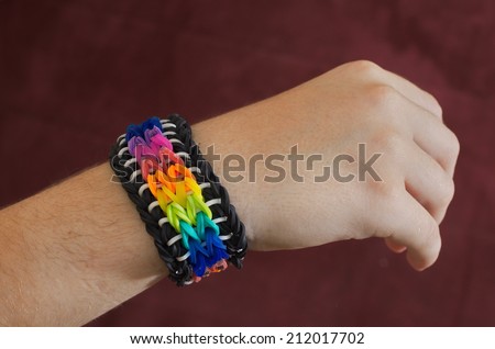 A child\'s hand decorated with rainbow color loom band rubber bracelet
