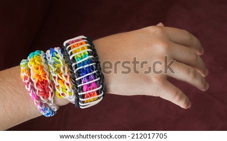 A child\'s hand decorated with rainbow color loom band rubber bracelets