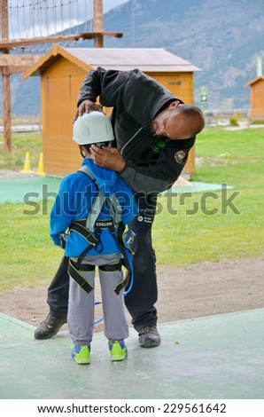 NATURLANDIA, ANDORRA - OCT 10, 2014: A 7 year old boy preparing to enter a challenging rope course sky trail in the Andorra Pyrenees Mountains by getting his gear fitted
