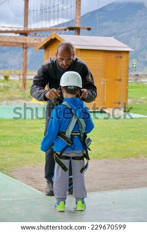 NATURLANDIA, ANDORRA - OCT 10, 2014: A 7 year old boy preparing to enter a challenging rope course sky trail in the Andorra Pyrenees Mountains by getting his gear fitted