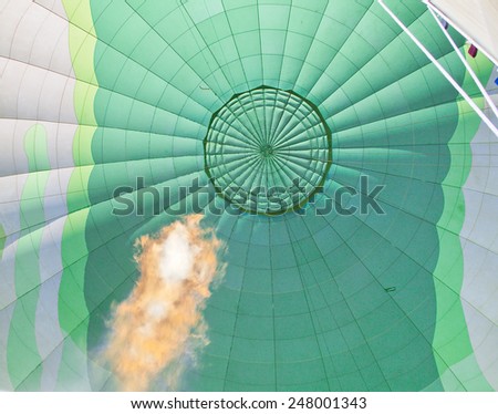 Huge gas flame heating the air in a green hot air balloon