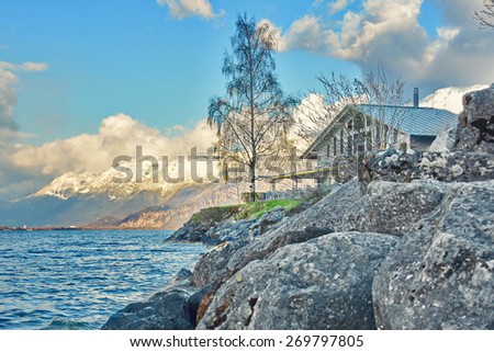 A wood cabin on the beautiful Lake Thun (Thunersee), Switzerland, with the snow capped Alps in the background