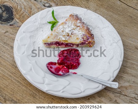 A piece of raspberry cheesecake on a wooden desk