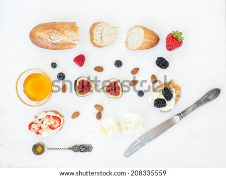 Cheese, bread and berries set on a white surface