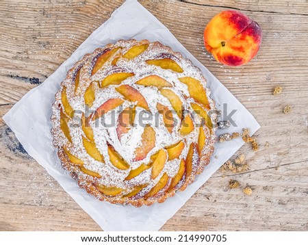 Peach pie with sugar powder over a piece of paper on a rough old wooden surface
