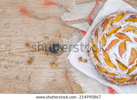 Peach pie with sugar powder over a linen table cloth on a  rough old wooden surface