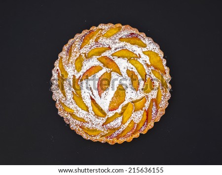 Peach pie with sugar powder over black background