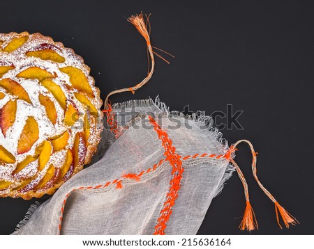 Peach pie with sugar powder over a linen table cloth  on a dark surface