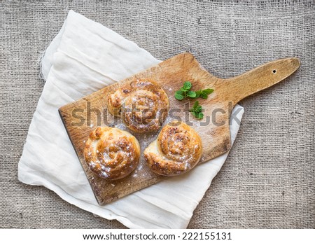 Cinnamon buns on a rustic wooden board over a sackcloth background