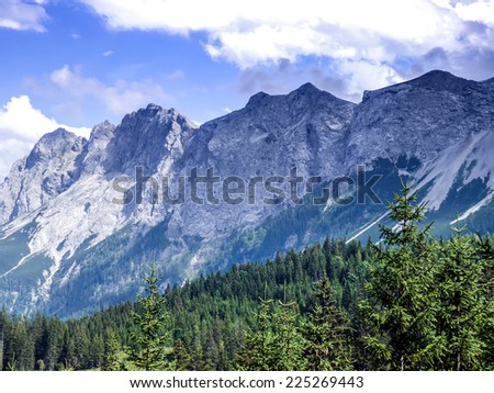 Alpine landscape: the view over the green valley, mountains and the sky in Austrian Alps