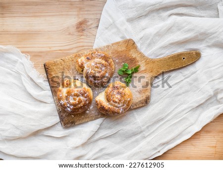Cinnamon buns on a rustic wooden board over a sackcloth background