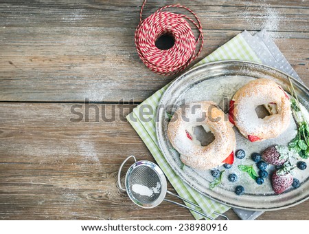 Custard ring pastry filled with cream-cheese, fresh strawberry and raspberry on a silver tray over a rough wood background with a copy space. Top view