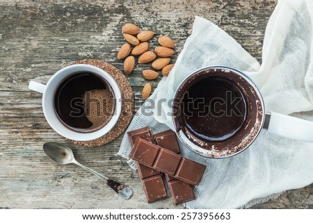 Coffee set. Cezve - coffee pot, with freshly brewed coffee, a coffee cup, a bar of chocolate and roasted almonds over a rough wood background. Top view