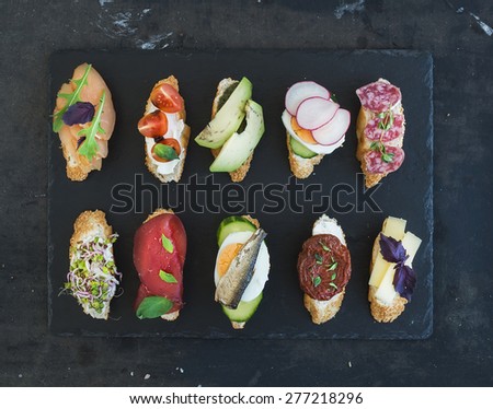 Mini sandwich set. Variety of small sandwiches on black backdrop, top view