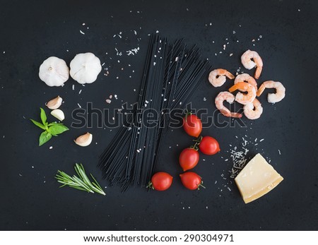 Ingredients for black pasta with seafood. Shrimps, spaghetti, basil, garlic, spices, parmesan cheese and  cherry-tomatoes on dark grunge backdrop, top view,