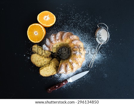 Moist orange bundt yogurt cake with sugar powder, dark grunge background. Top view