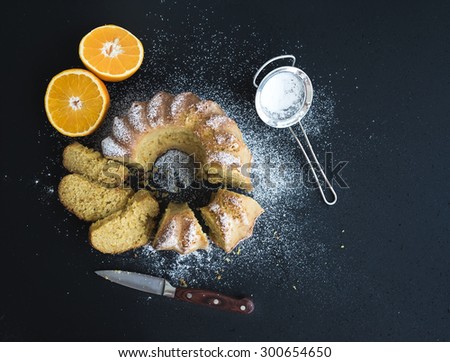 Moist orange bundt yogurt cake with sugar powder, dark grunge background. Top view