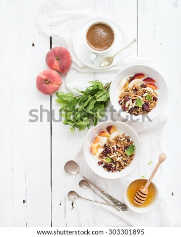 Healthy breakfast. Bowl of oat granola with yogurt, fresh fruit, mint and honey. Cup of coffee, vintage silverware. Top view, copy space
