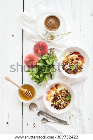 Healthy breakfast. Bowl of oat granola with yogurt, fresh fruit, mint and honey. Cup of coffee, vintage silverware. Top view