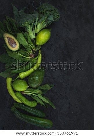 Raw green vegetables set. Broccoli, avocado, pepper, spinach, zucchini, lime on  dark stone background, top view, copy space
