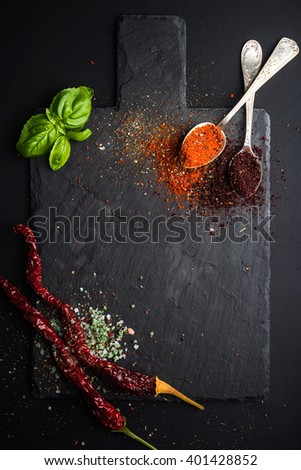 Herbs and spices on black slate stone board over dark background. Top view, copy space