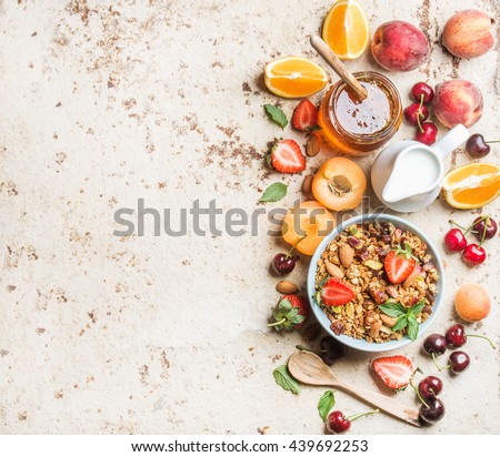 Healthy breakfast ingredients. Bowl of oat granola with milk, fresh fruit, berries and honey. Top view, copy space