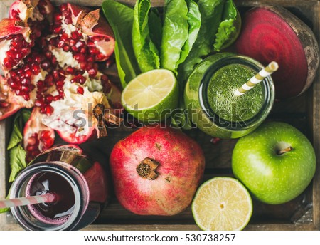 Close-up of green and purple fresh juices with fruit, greens, vegetables in wooden tray, top view, selective focus. Detox, dieting, clean eating, vegetarian, vegan, fitness, healthy lifestyle concept