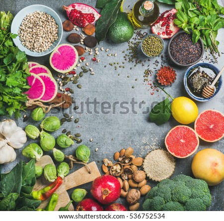 Clean eating concept over grey concrete background, top view, copy space. Variety of vegetables, fruit, seeds, cereal, bean, spices, superfood, herbs, condiment for vegan, raw diet or gluten free diet