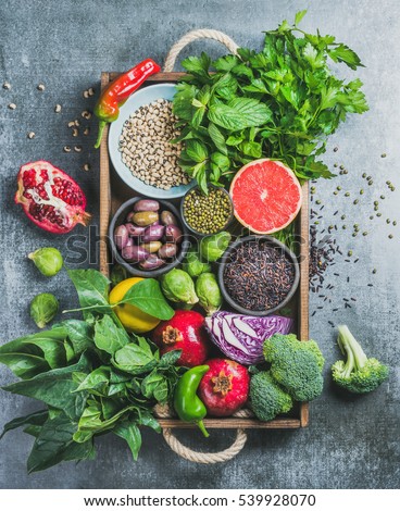 Vegetables, fruit, seeds, cereals, beans, spices, superfoods, herbs, condiment in wooden box for vegan, gluten free, allergy-friendly, clean eating or raw diet. Grey concrete background and top view
