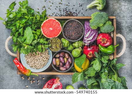 Vegetables, fruit, seeds, cereals, beans, spices, superfoods, herbs, condiment in wooden box for vegan, gluten free, allergy-friendly, clean eating and raw diet. Grey concrete background and top view