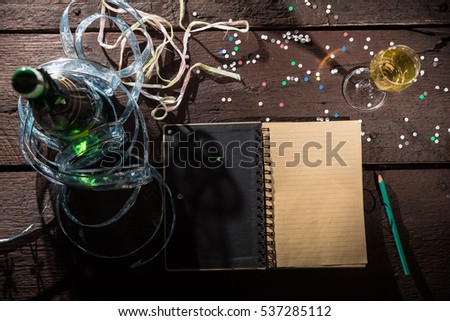 Open notepad on the old table ready to write New Year\'s resolutions, Champagne and glass, confetti. New years concept.
