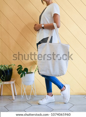 woman showing white totebag. Tote bag mock up for designer. In fun background, pink yellow and green pallete