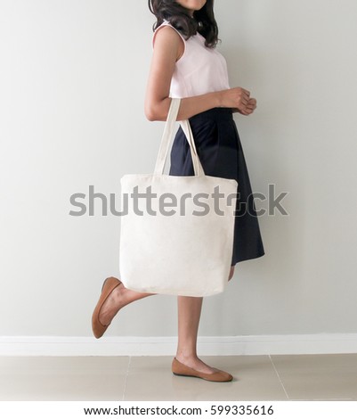 Girl is holding blank canvas tote bag, design mockup. Handmade shopping tote bag for girls.