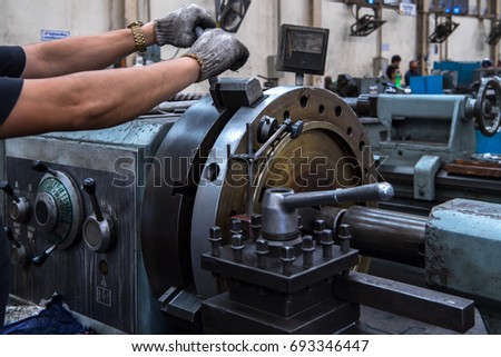 Close up hand  heavy industrial worker is working on metal work factory process by performing mechanical turning operation at machine for steel structure industry