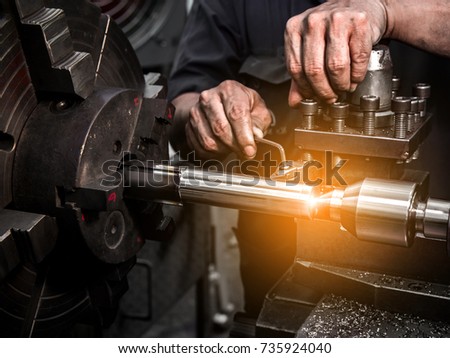 Close up hand  heavy industrial worker is working on metal work factory process by performing mechanical turning operation at machine for steel structure industry