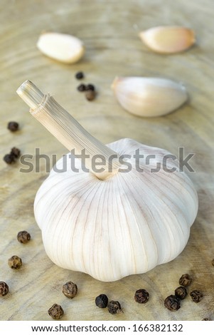 White garlic and black pepper on wood.