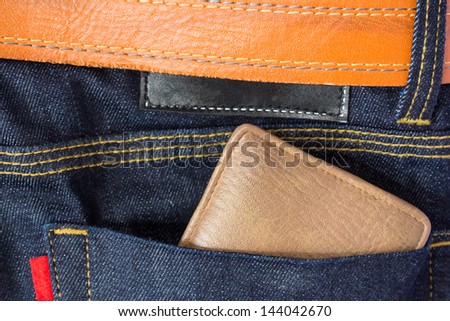 Brown wallet in blue jeans and brown leather belt