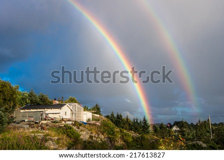 Rainbow in sky over lonely farm house in Oygarden islands in Horoland in Norway
