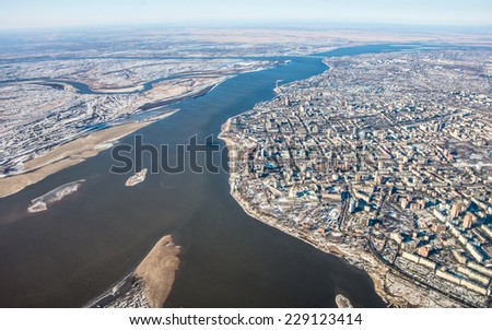 Airplane panoramic view of great Amur (Heilong Jiang) river, Khabarovsk city  and bridge which is part of Trans-Siberian railway in Khabarovsk district in Far East of Russia with first winter snow