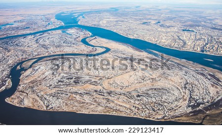 Airplane panoramic view of great Amur (Heilong Jiang) river, Khabarovsk city  and bridge which is part of Trans-Siberian railway in Khabarovsk district in Far East of Russia with first winter snow