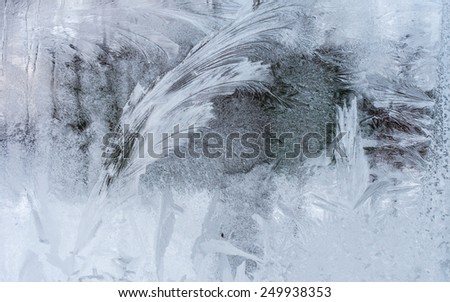 Window glass with feather-like pattern, drawn by hoarfrost, taken from inside on the building in cold winter weather - abstract winter background