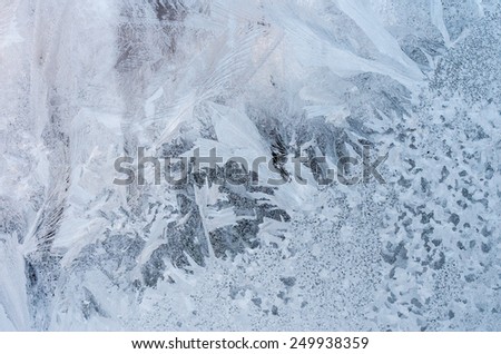 Window glass with hoarfrost drawings, taken from inside on the building in cold winter weather - abstract winter background