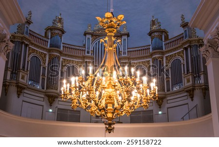 Golden chandelier with candles and organ (musical instrument) in Helsinki Lutheran cathedral (St. Nicolas church), Finland