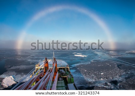 Research ship going under white rainbow through the ice in Arctic ice in East-Siberian sea, Arctic ocean. White rainbow is rare meteorological phenomenon.