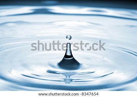 Water drop on a body of water creating ripples.