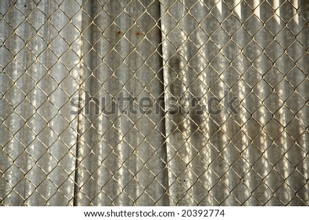 Metal fence with corragated metal panels behind it